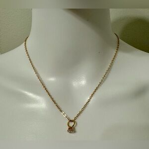 A graceful gold-colored necklace with a mini ring pendant with a zircon crystal.